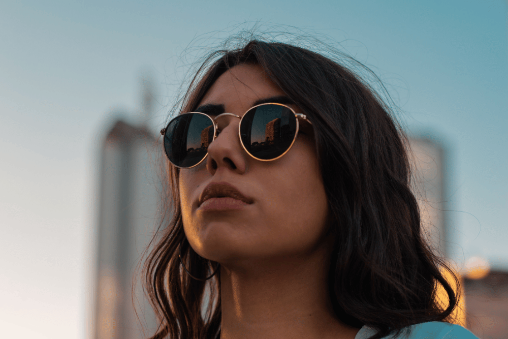 woman outside wearing sunglasses and staring off into the distance