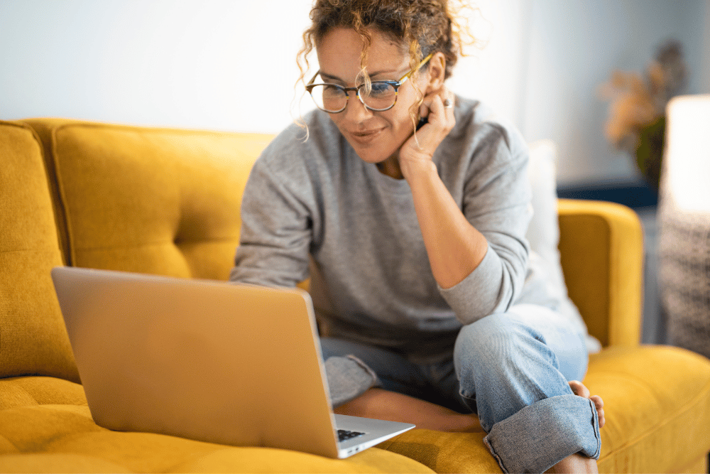 a woman sitting on her couch looking at her computer