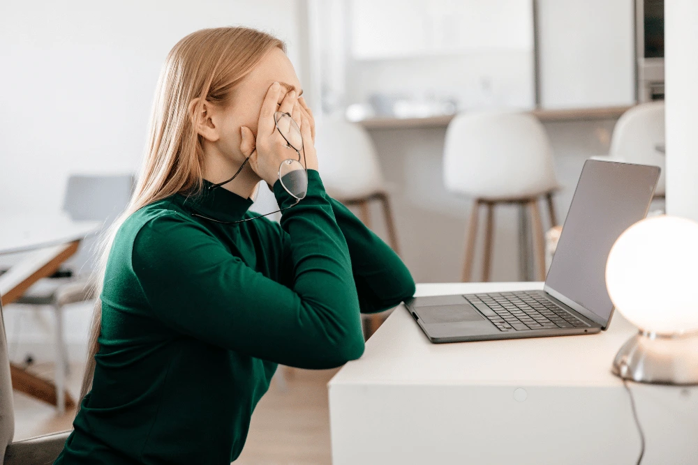 a woman sitting at her desk and suffering from digital eye strain